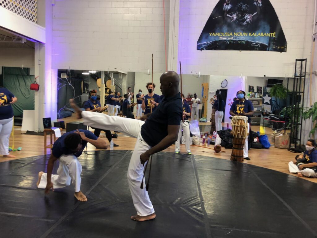 A man gives a kick while the other ducks and evades